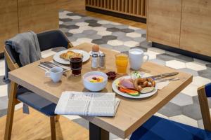 a wooden table with plates of food and drinks on it at Holiday Inn Express - Goettingen, an IHG Hotel in Göttingen