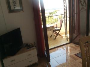 a living room with a television and a balcony at Villa Jadranka in Rab