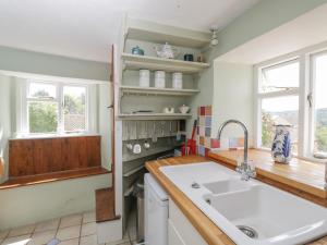 eine Küche mit einem Waschbecken und einem Fenster in der Unterkunft Athelstan Cottage in Stroud