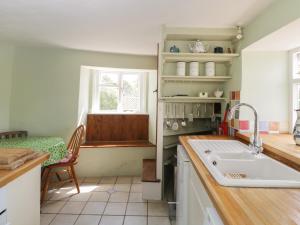 a kitchen with a sink and a table and a window at Athelstan Cottage in Stroud