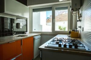 cocina con fogones horno superior junto a una ventana en Casa das Aguarelas - Apartamentos, en Ericeira