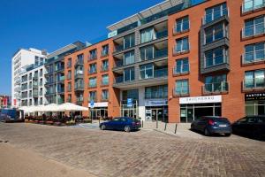 a large brick building with cars parked in front of it at Elite Apartments Waterlane Swimming Pool&aSpa in Gdańsk