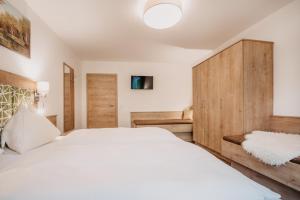 a bedroom with a white bed and a wooden cabinet at DAS "Bergzeit" - Appartements in Wagrain