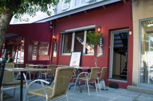 un bâtiment rouge avec des tables et des chaises devant lui dans l'établissement Aux Platanes, à Poligny