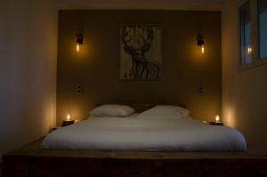 a bedroom with a large white bed with two candles at Aux Platanes in Poligny