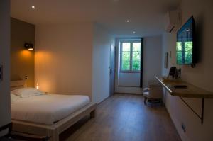 um quarto com uma cama, uma secretária e uma janela em Aux Platanes em Poligny
