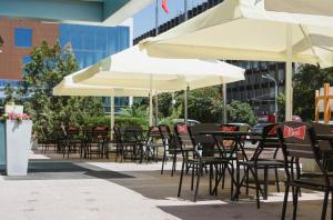 eine Gruppe von Tischen und Stühlen mit Sonnenschirmen in der Unterkunft Don Plaza Congress Hotel in Rostow am Don