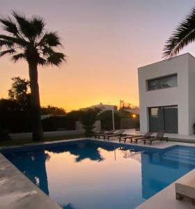 a villa with a swimming pool in front of a sunset at Can miami modern house close platja den bossa in Sant Jordi