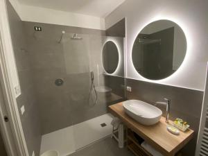 a bathroom with a sink and a shower with a mirror at Rooms ai Poggi in Bardolino