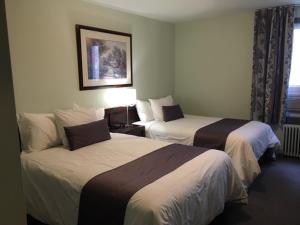 a hotel room with two beds and a window at Auberge Centre Ville in Saguenay +32 photos