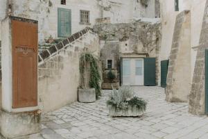 un edificio antiguo con algunas plantas en un patio en Pietragialla en Matera