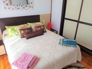 1 dormitorio con 1 cama blanca grande con almohadas coloridas en HABITACIONES CON WC PROPIO, COCINA COMPARTIDA Sopela LBI217, en Sopelana