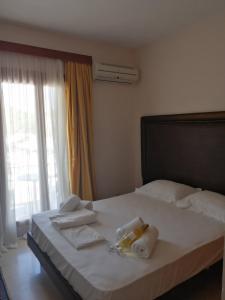 1 dormitorio con 1 cama con toallas y ventana en Verdelis Inn, en Palaia Epidavros
