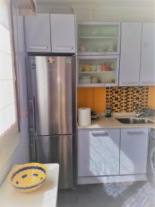 una cocina con nevera de acero inoxidable y armarios blancos en HABITACIONES CON WC PROPIO, COCINA COMPARTIDA Sopela LBI217, en Sopelana