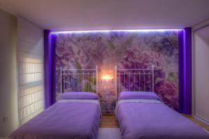 2 camas en una habitación con luces moradas en Capitolio Apartamentos Turísticos Parking, en Mérida