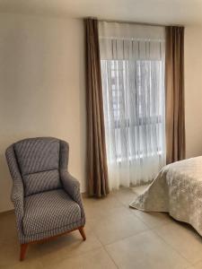 a bedroom with a chair and a bed and a window at KRésidence Appartement Neuf Saint-Louis in Saint-Louis