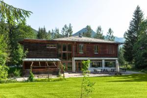 une grande maison en bois avec une pelouse verte dans l'établissement Sporthotel Grünau - Wimmergreuth, à Grünau im Almtal