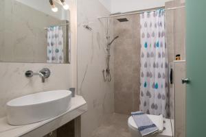La salle de bains blanche est pourvue d'un lavabo et d'une douche. dans l'établissement Fantasia Studios and Apartments, à Neos Marmaras