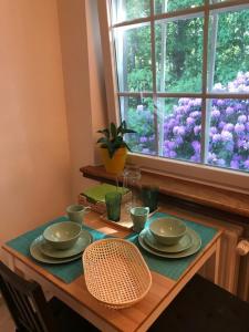 a table with plates and cups and a window with purple flowers at Boslucht Leuven in Heverlee