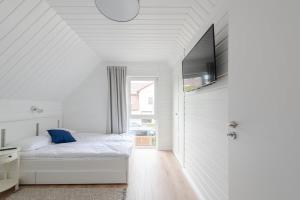 a white bedroom with a bed and a television at Domki Villa Hoff Resort in Trzęsacz