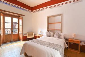 a bedroom with a white bed and a window at Hotel Meson Cuevano in Guanajuato