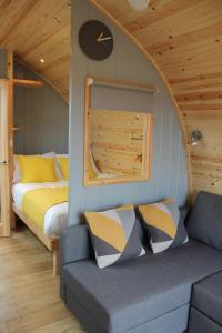 Habitación con sofá, cama y reloj en North Star Glamping en Lybster