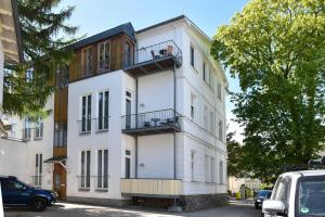a white building with a balcony on a street at Villa Lucie Else 06 in Heringsdorf