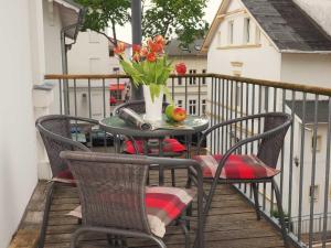 una mesa con sillas y un jarrón de flores en el balcón en Villa Lucie Else 06, en Heringsdorf