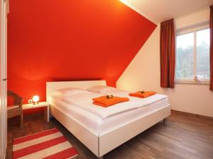 1 dormitorio con 1 cama con pared de color naranja en Ferienhaus Sonneninsel 5c, en Korswandt