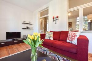 un sofá rojo en una sala de estar con un jarrón de flores en Villa Emmy Wohnung 8, en Heringsdorf