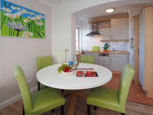 a kitchen with a white table and green chairs at Villa Vineta Wohnung 206 in Ahlbeck