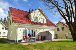 una casa con techo rojo, mesa y sillas en Ferienhaus Birgit, en Korswandt