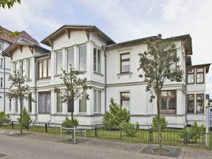 una gran casa blanca con una valla negra en Haus Meerblick Wohnung 7, en Ahlbeck