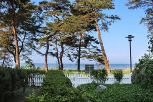 een wit hek met bomen en de oceaan op de achtergrond bij Villa Strandperle 17 in Bansin