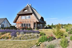 ein Haus mit einem Strohdach und einem Garten in der Unterkunft Ferienhaus Mühlenblick in Pudagla