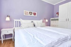a bedroom with a large white bed with purple walls at Sonnenpark 01 in Korswandt