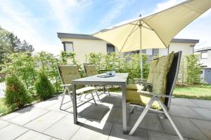 a table and chairs with an umbrella on a patio at Sonnenpark 01 in Korswandt