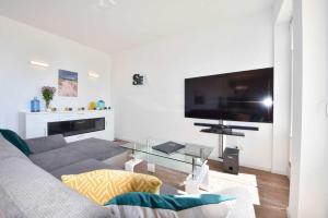 een woonkamer met een grijze bank en een grote flatscreen-tv bij Ferienwohnung mit Haffblick 01 in Kamminke