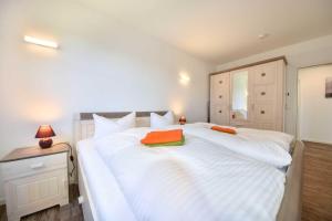 een groot wit bed met 2 oranje kussens erop bij Ferienwohnung mit Haffblick 01 in Kamminke