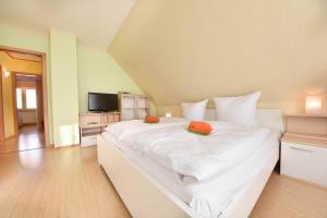 ein großes weißes Bett mit zwei orangenen Kissen darauf in der Unterkunft (18) Haus Thomas in Heringsdorf
