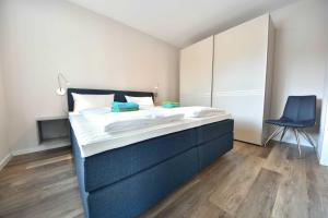 um quarto com uma cama e uma cadeira azul em Haus Seven Seas - Wohnung Pazifik em Heringsdorf