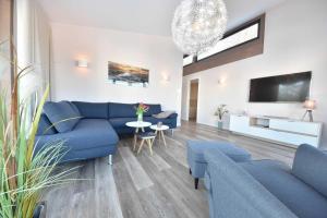 uma sala de estar com sofás azuis e uma televisão em Haus Seven Seas - Wohnung Atlantik em Heringsdorf