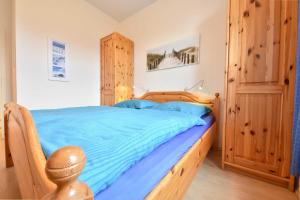 ヘリングスドルフにあるVilla Inge Wohnung 9のベッドルーム1室(木製ベッド1台、青いシーツ付)