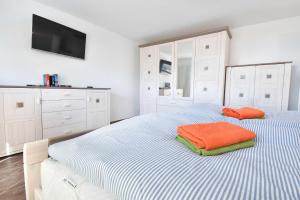 a white bedroom with a bed with an orange pillow at Ferienhaus Insel-Paradies in Kamminke
