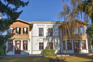 een groot wit huis met rode deuren en ramen bij Villa Lamora 03 in Heringsdorf