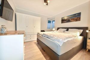 a bedroom with a large white bed and a kitchen at Sonnenpark 15 in Korswandt