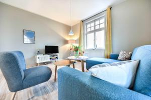 - un salon avec 2 chaises bleues et une télévision dans l'établissement Haus Kogge Wohnung 1, à Heringsdorf