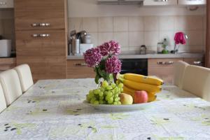 einen Tisch mit einem Obstteller und einer Vase Blumen in der Unterkunft Apartman Robi in Nova Vas