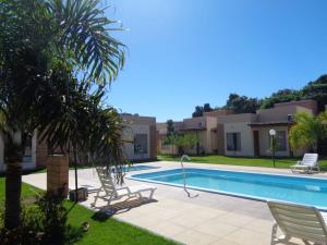 uma villa com piscina e palmeiras em Vila Axé Flat 05 Riviera em Prado