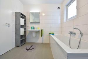 ein weißes Badezimmer mit Badewanne und Waschbecken in der Unterkunft Haus Neuhof 01 in Heringsdorf